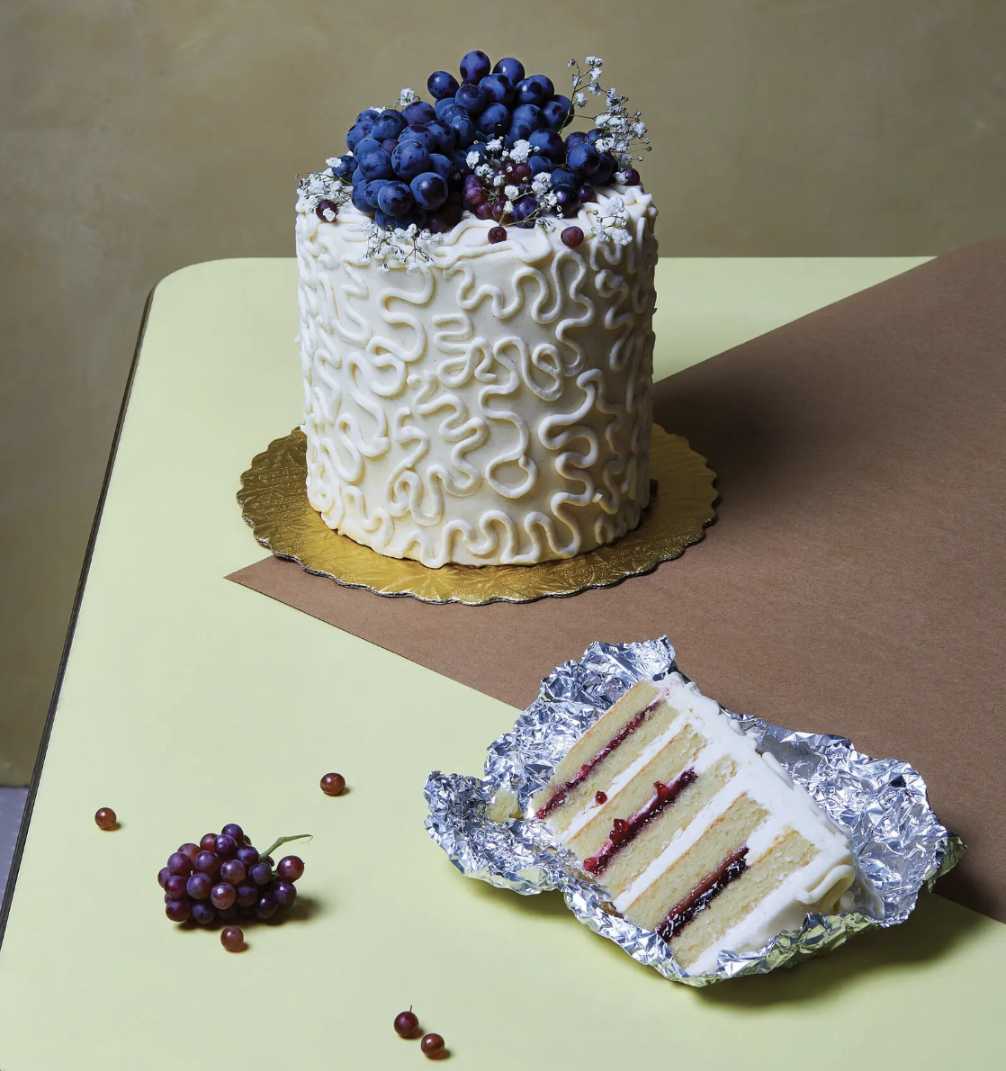 Photo of pastry chef Paola Velez’s six-layer cake, which is topped with Concord grapes and baby’s breath, draws on the colors of the suffragists: purple, green and white. 