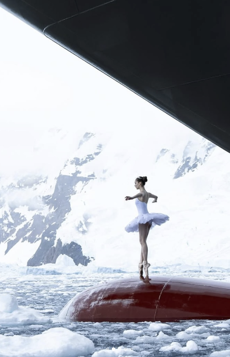 Photo of French ballerina Victoria Dauberville dancing on top of a ship’s bow surrounded by floating ice in Antarctica.