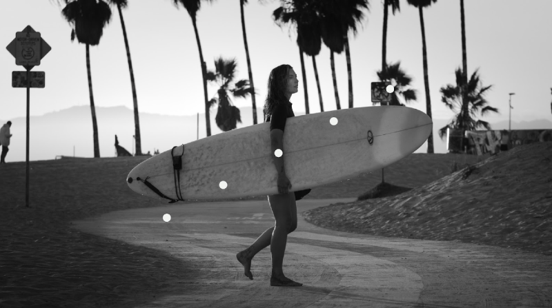 Photo of a surfer walking while carrying her board.
