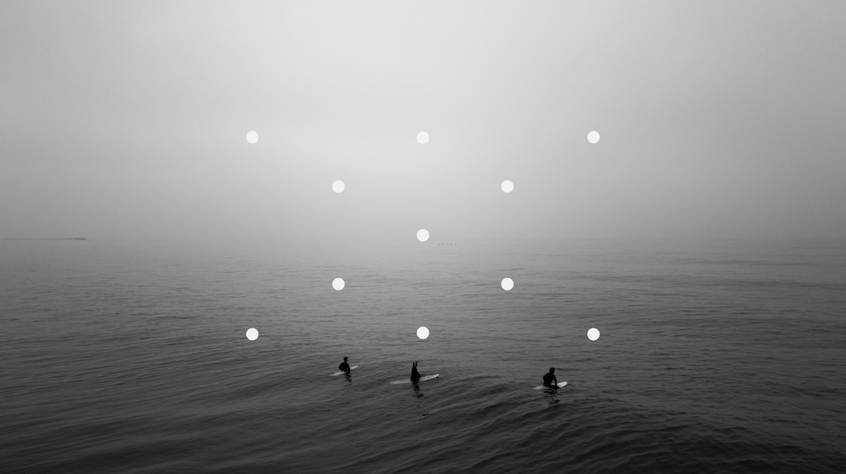 Three surfers in the ocean, overlaid with a dot graphic.