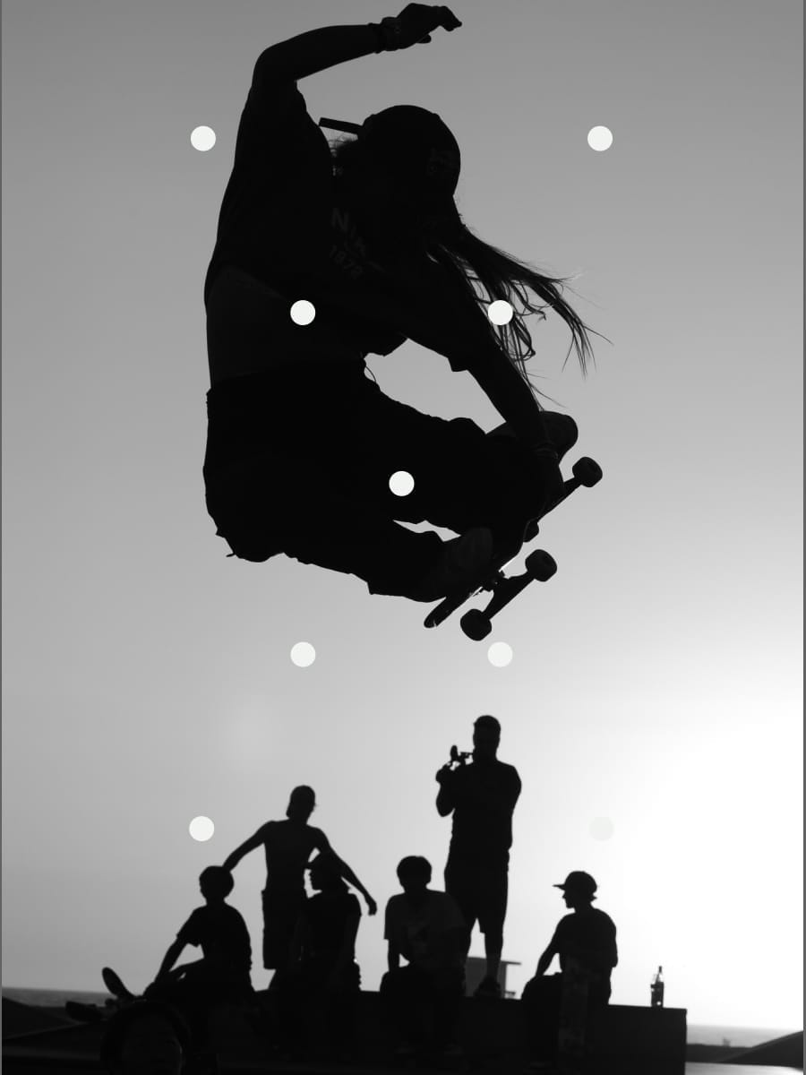A silhouetted skateboarder leaps over a group of skateboarders.